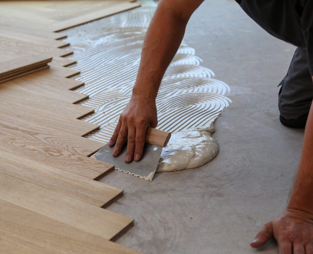 Worker laying parquet flooring. Worker installing wooden laminate flooring Worker laying parquet flooring. Worker installing wooden laminate flooring.